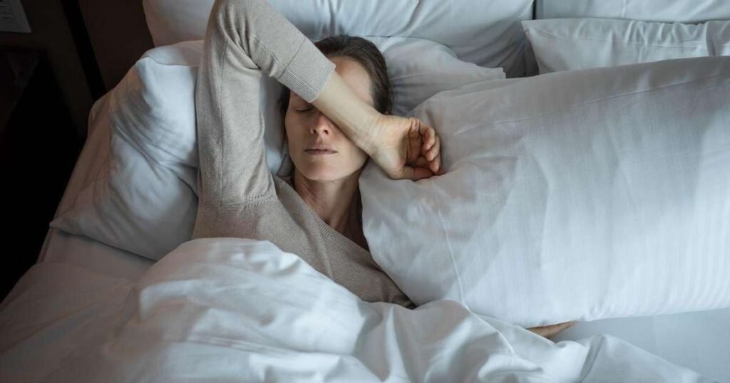Pessoa acordando à noite com sintomas inquietantes, como suor e dor, indicando possibilidade de alerta para câncer.