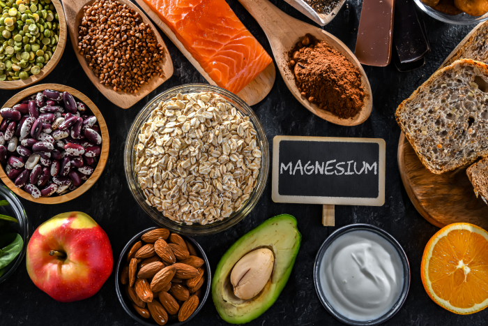 Mulher feliz na menopausa segurando um suplemento de magnésio e vegetais ricos em magnésio