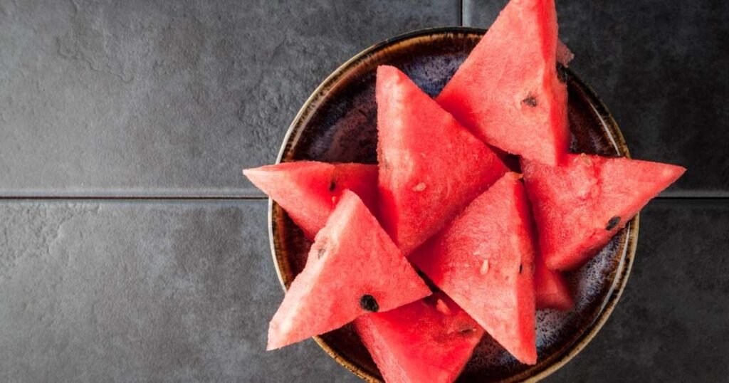 Chá de melancia em um copo com fatias de melancia ao fundo