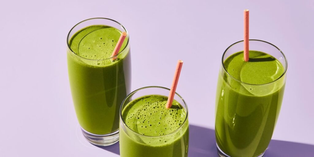 Smoothie de coco e couve servido em um copo, decorado com uma fatia de banana e folhas de couve.